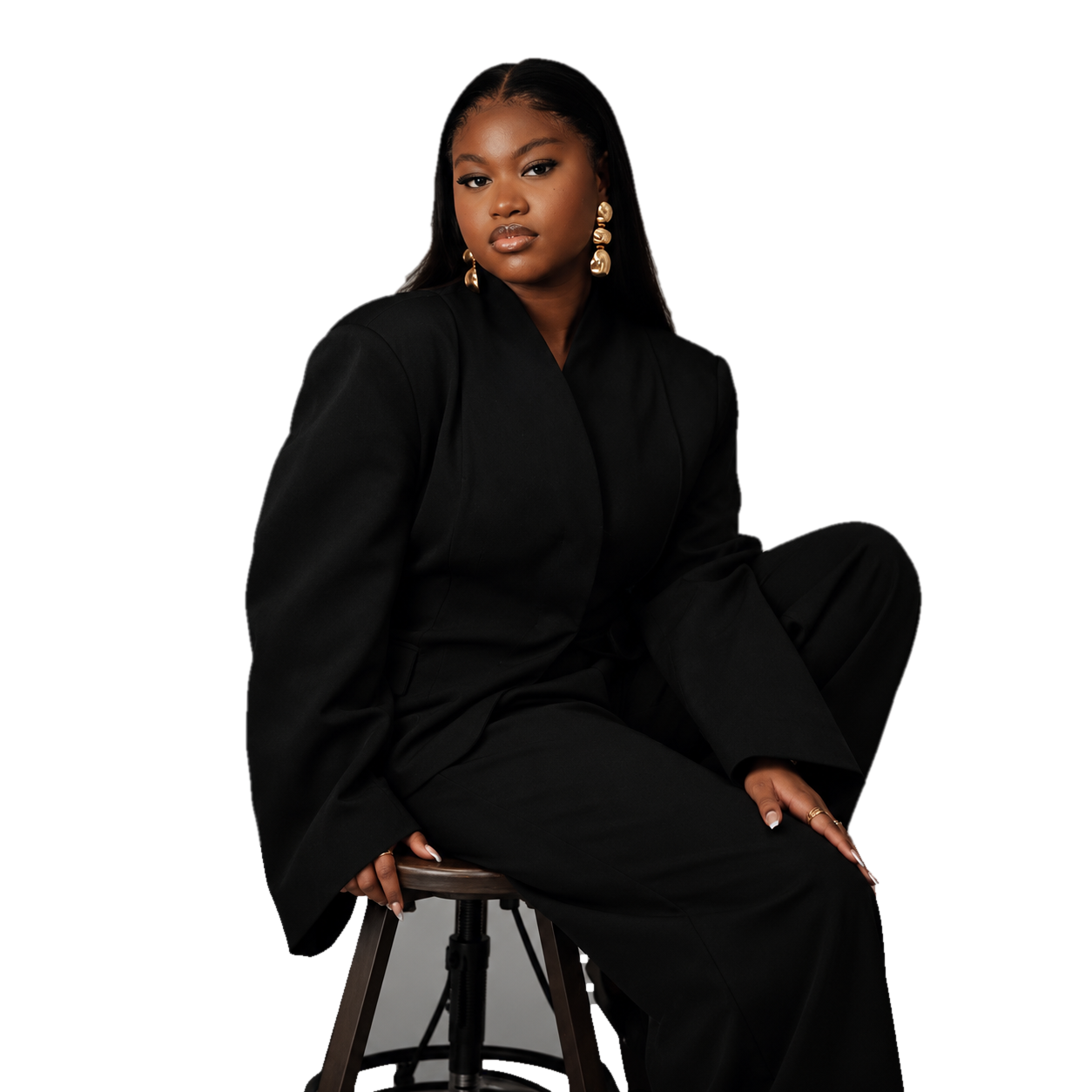 Ruth, fondatrice de Keelah Studios, assise sur un tabouret en tailleur noir